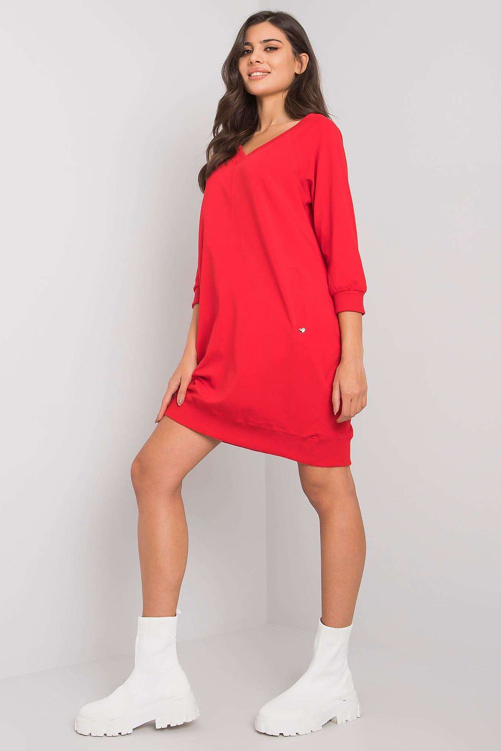 Woman wearing a red dress with white socks on a plain background