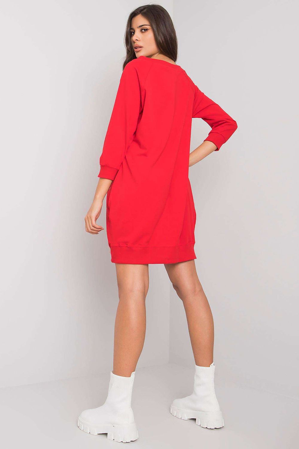 Woman wearing a red dress with white sneakers on a light gray background