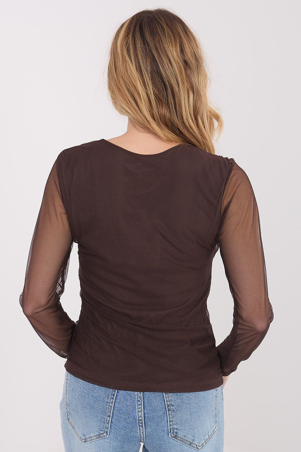 Person wearing a brown long-sleeve top with sheer sleeves on a white background
