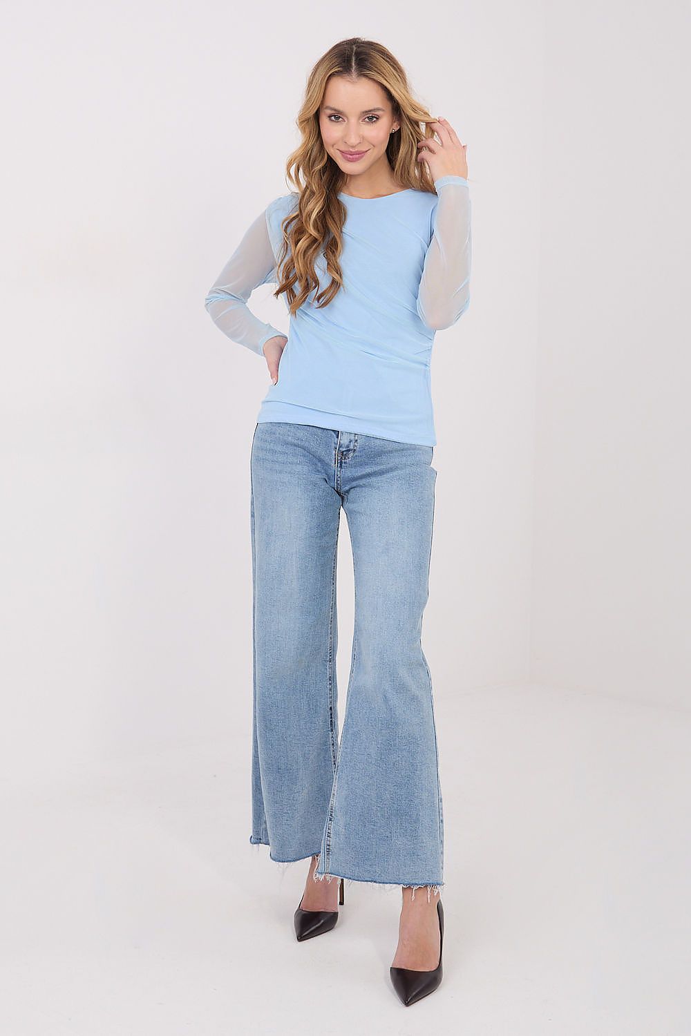 Woman wearing a light blue sweater and jeans on a white background