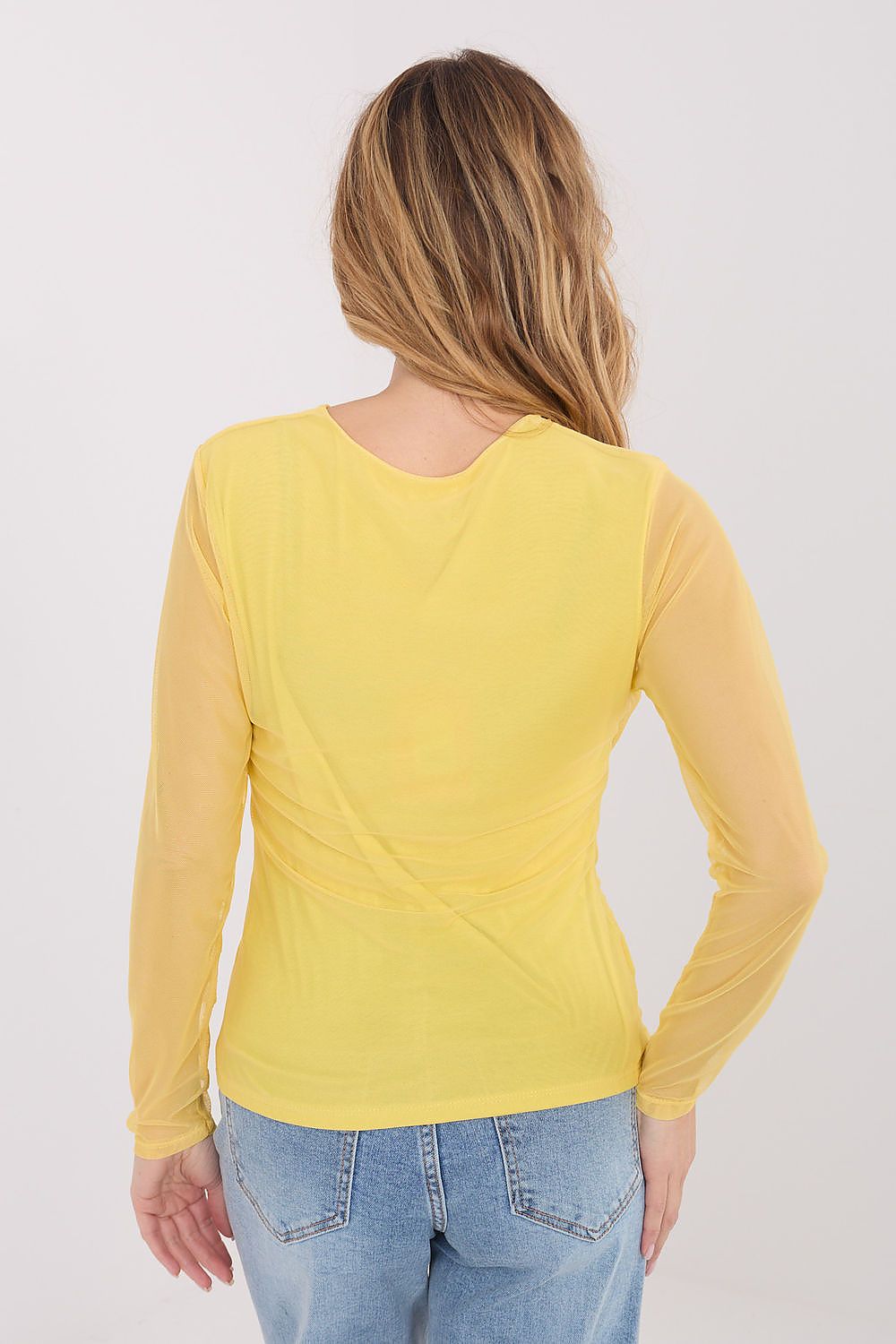 Person wearing a yellow long-sleeve top and blue jeans on a white background