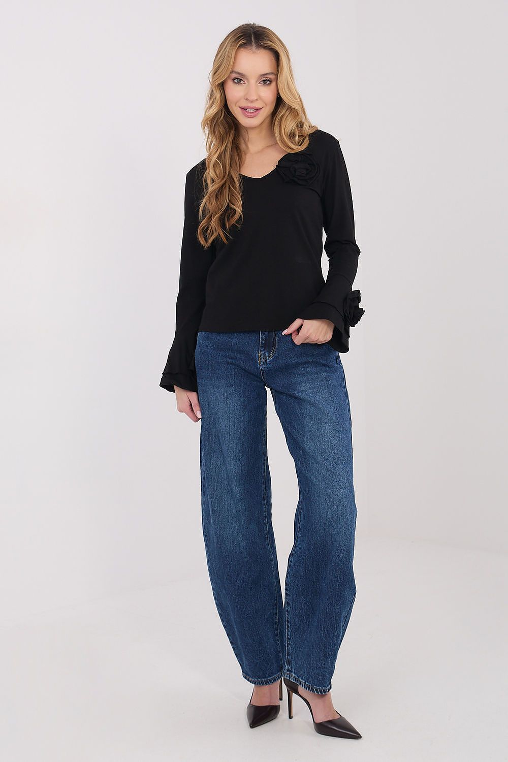 Woman wearing a black top and blue jeans on a white background
