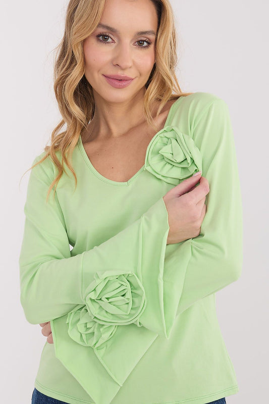 Woman wearing a light green blouse with ruffled sleeves on a white background