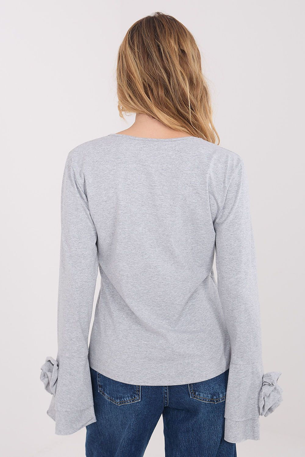 Person wearing a gray long-sleeve top with rolled-up cuffs on a white background