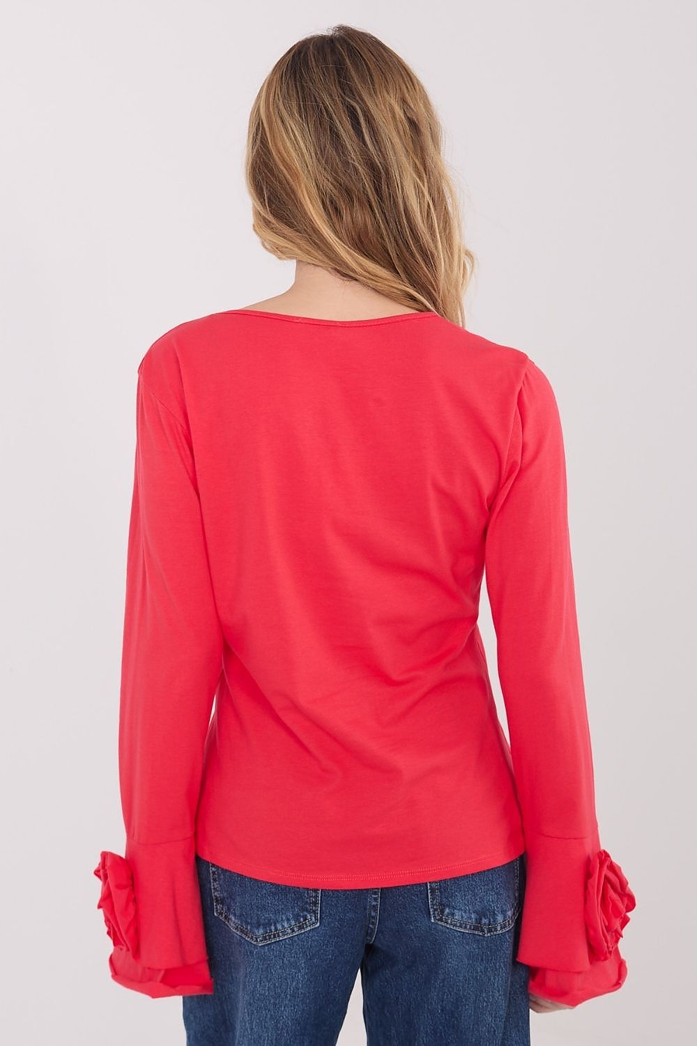 Red long-sleeve top with ruffled cuffs worn by a person on a white background