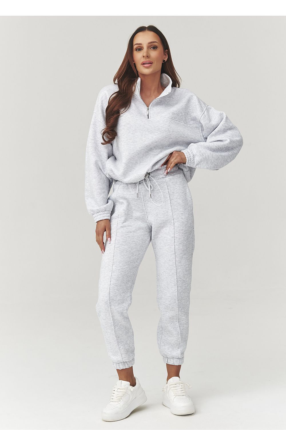Woman wearing a gray tracksuit on a white background