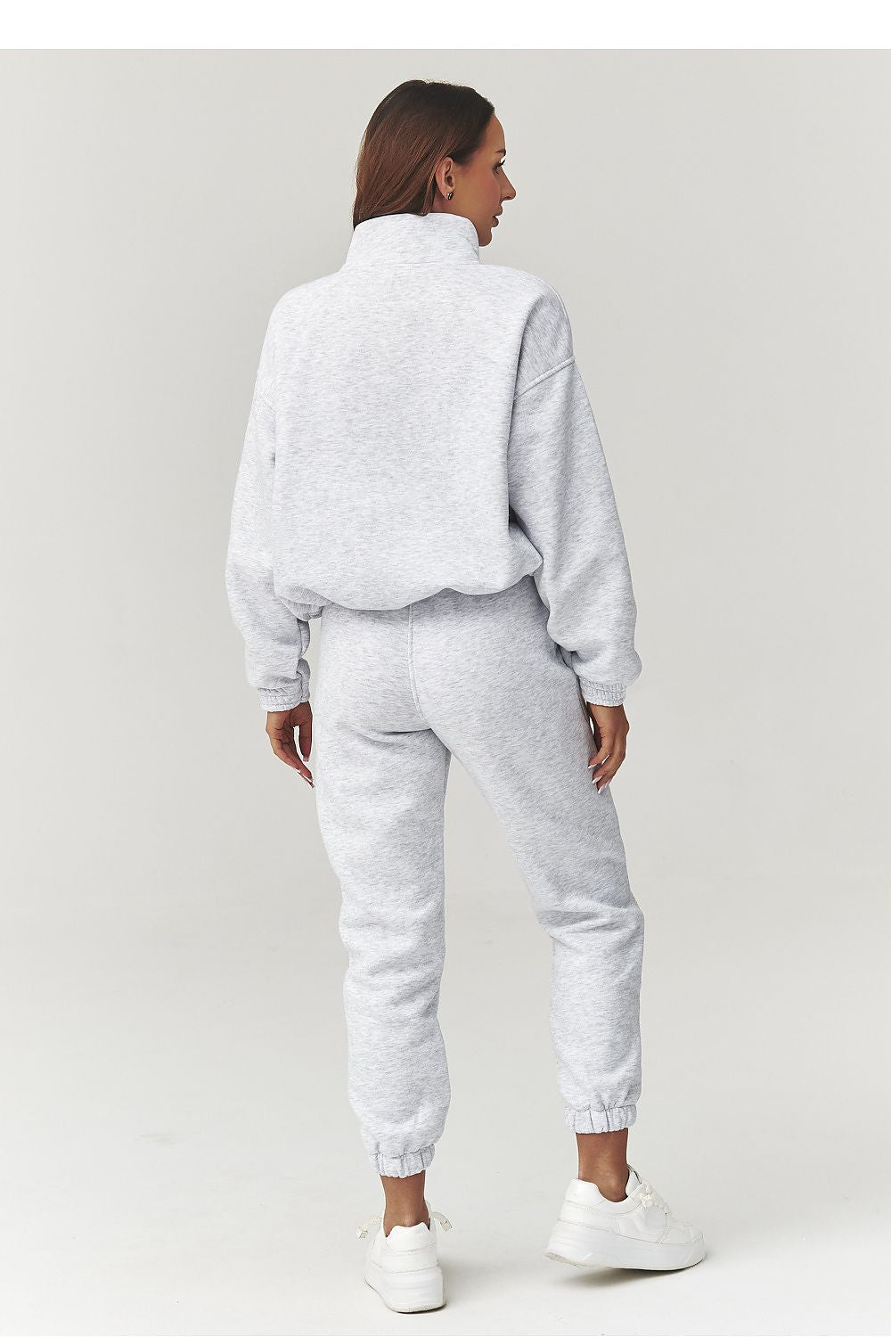 Person wearing a gray tracksuit on a white background