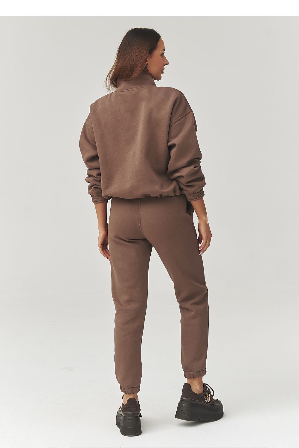 Person wearing a brown tracksuit on a white background