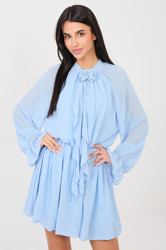 Woman wearing a light blue dress with sheer sleeves against a white background