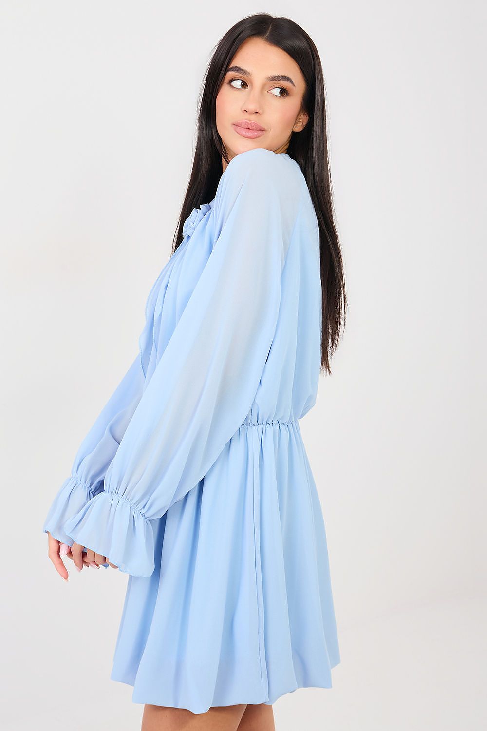 Woman wearing a light blue dress with long sleeves on a white background