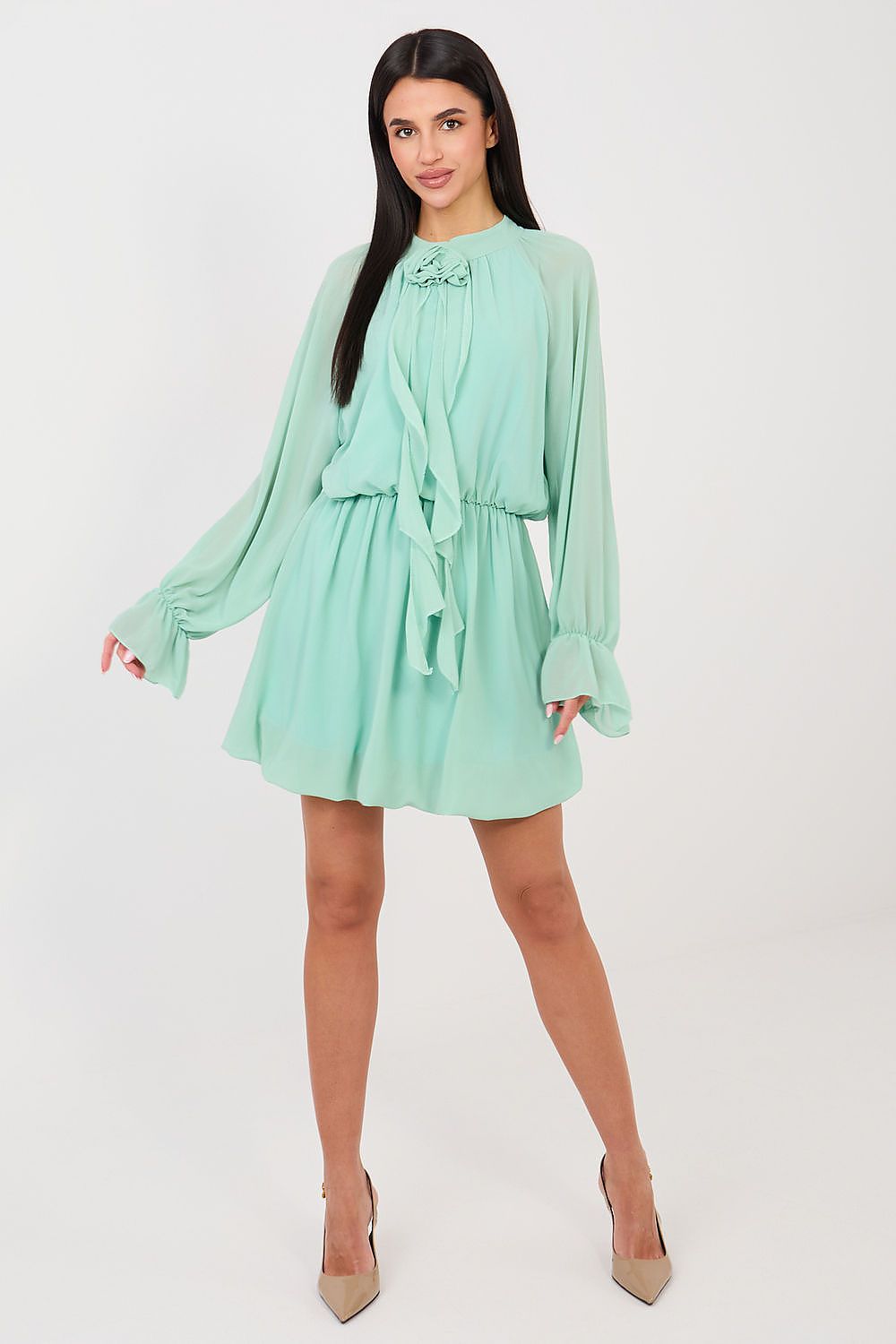 Woman wearing a light green dress with long sleeves on a white background