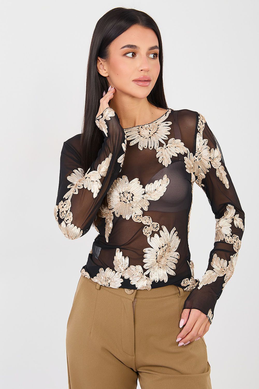 Woman wearing a sheer top with floral embroidery on a white background