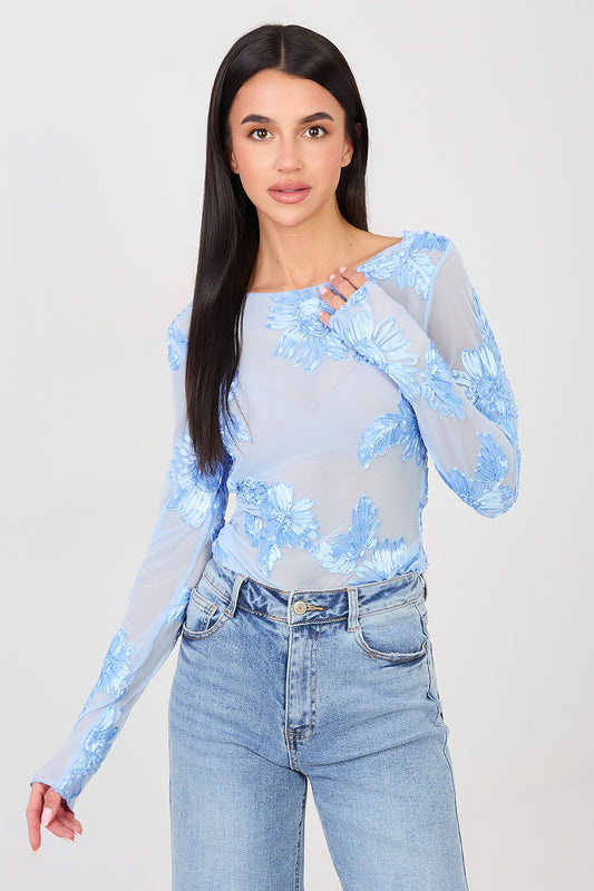 Woman wearing a light blue sequin top and jeans on a white background