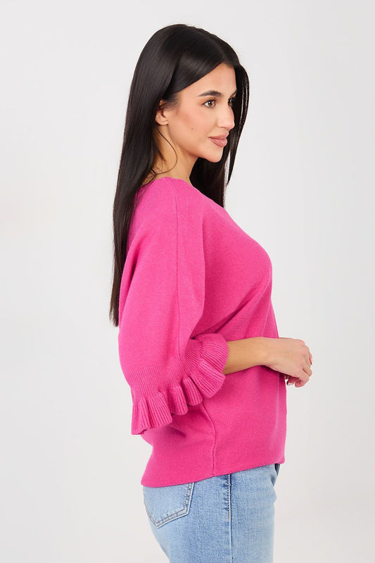 Woman wearing a bright pink sweater and light blue jeans on a white background