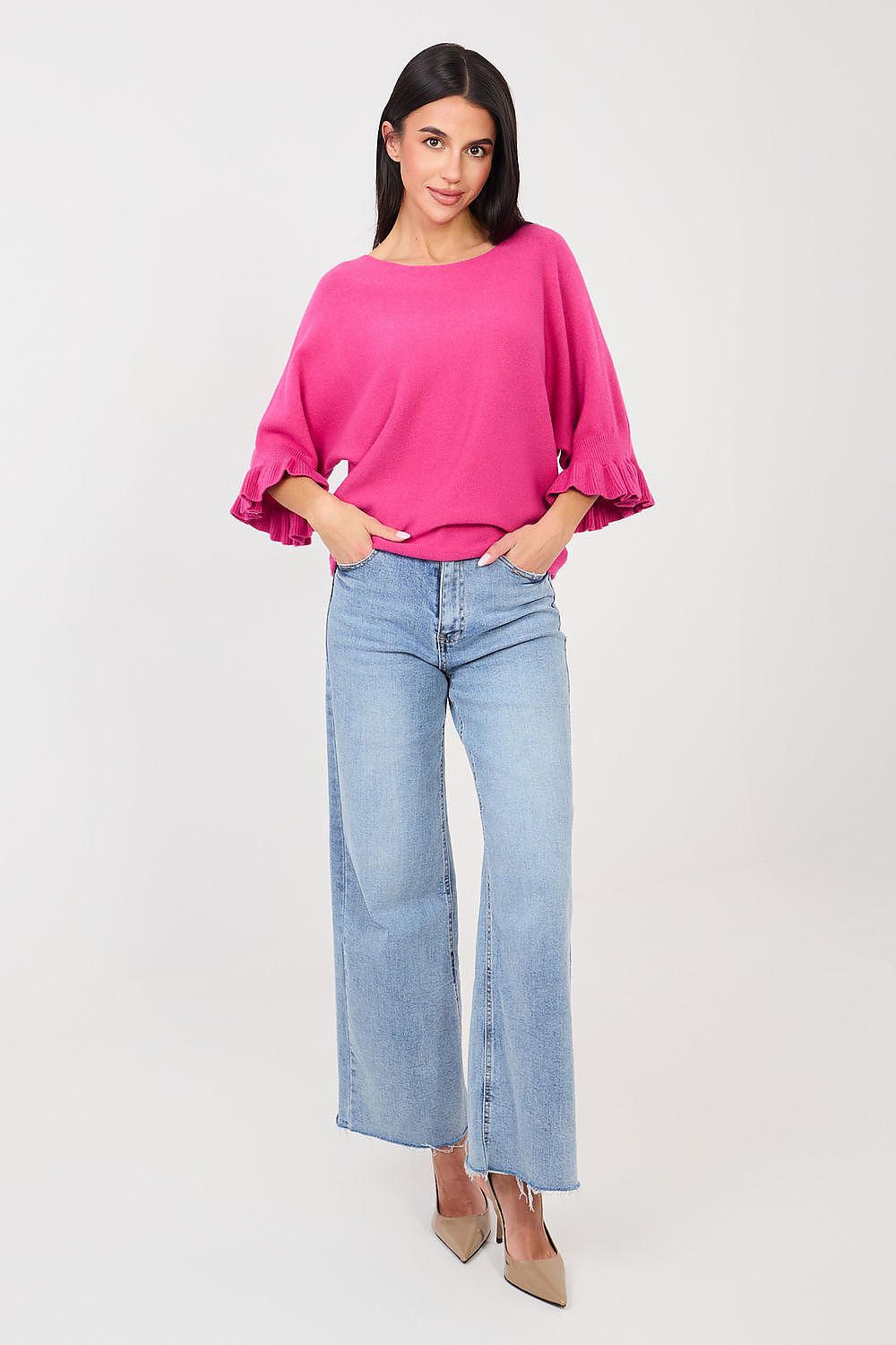 Woman wearing a bright pink top and light blue jeans on a white background