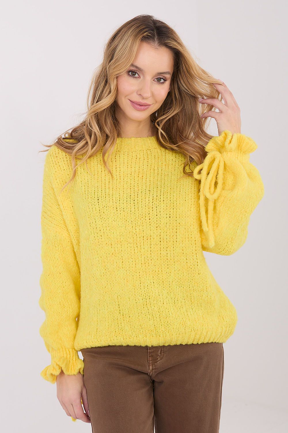 Woman wearing a yellow sweater with balloon sleeves on a white background