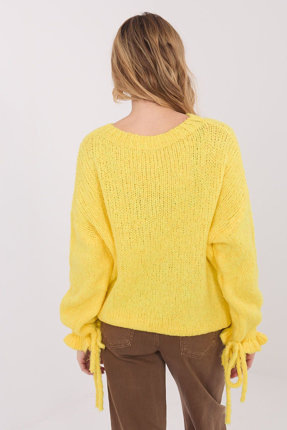 Person wearing a yellow sweater with tied sleeves on a white background