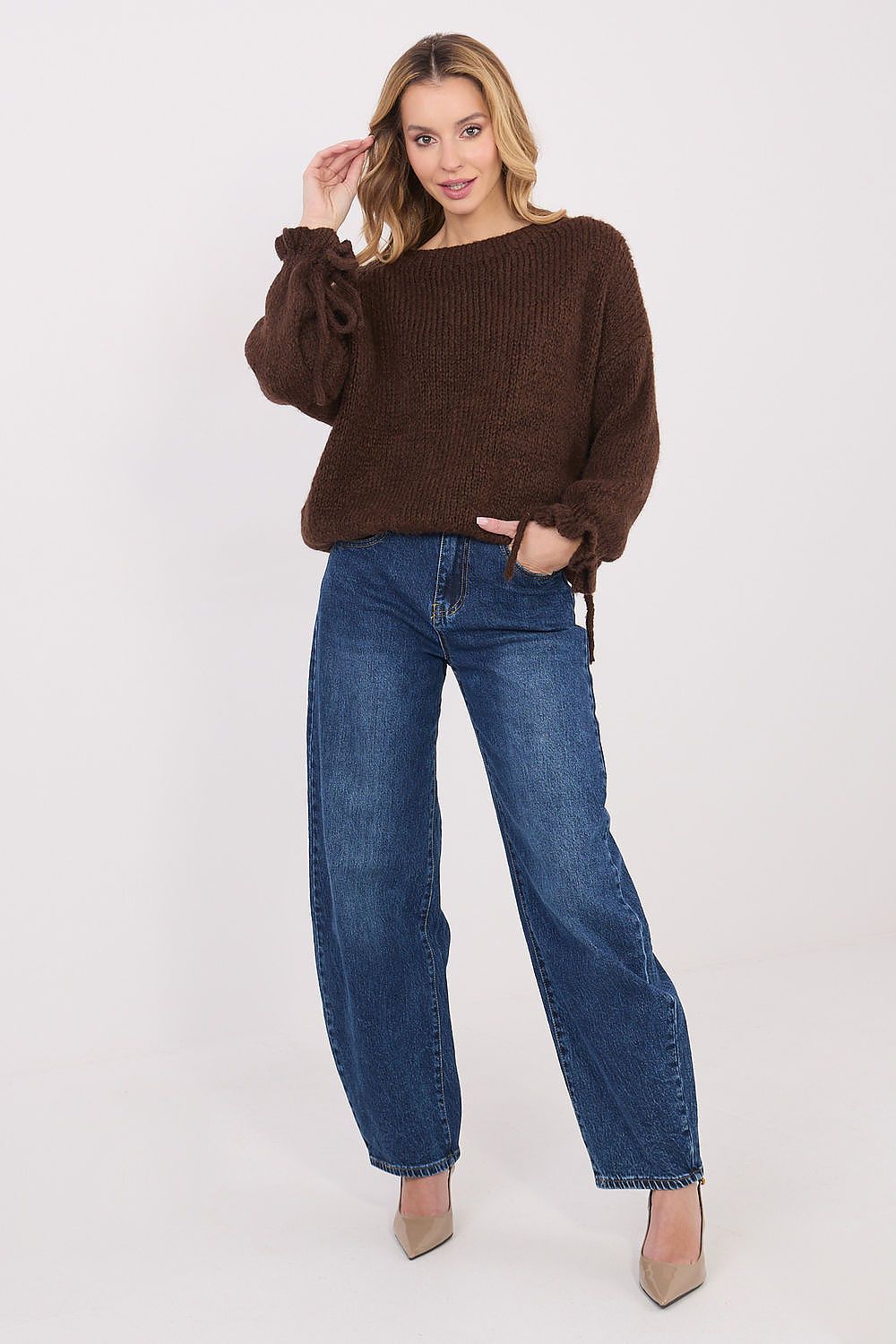 Woman wearing a brown sweater and blue jeans on a white background