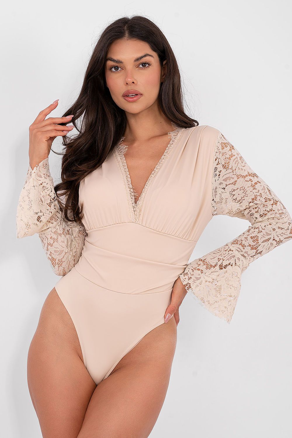 Woman wearing a beige swimsuit with lace sleeves on a white background