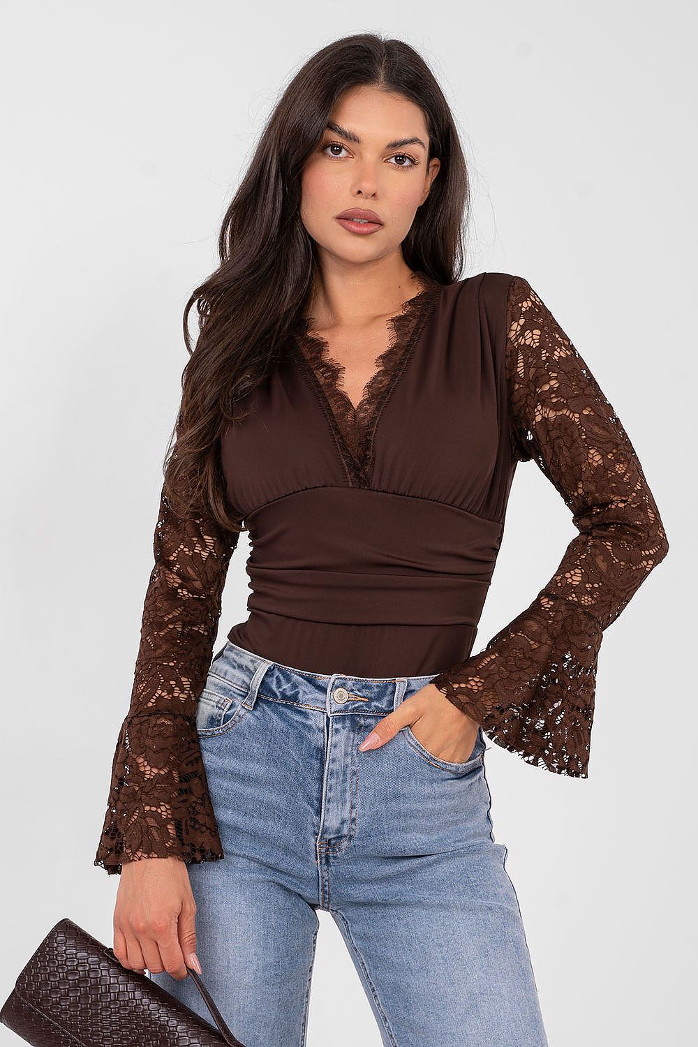 Woman wearing a brown lace top and blue jeans on a white background