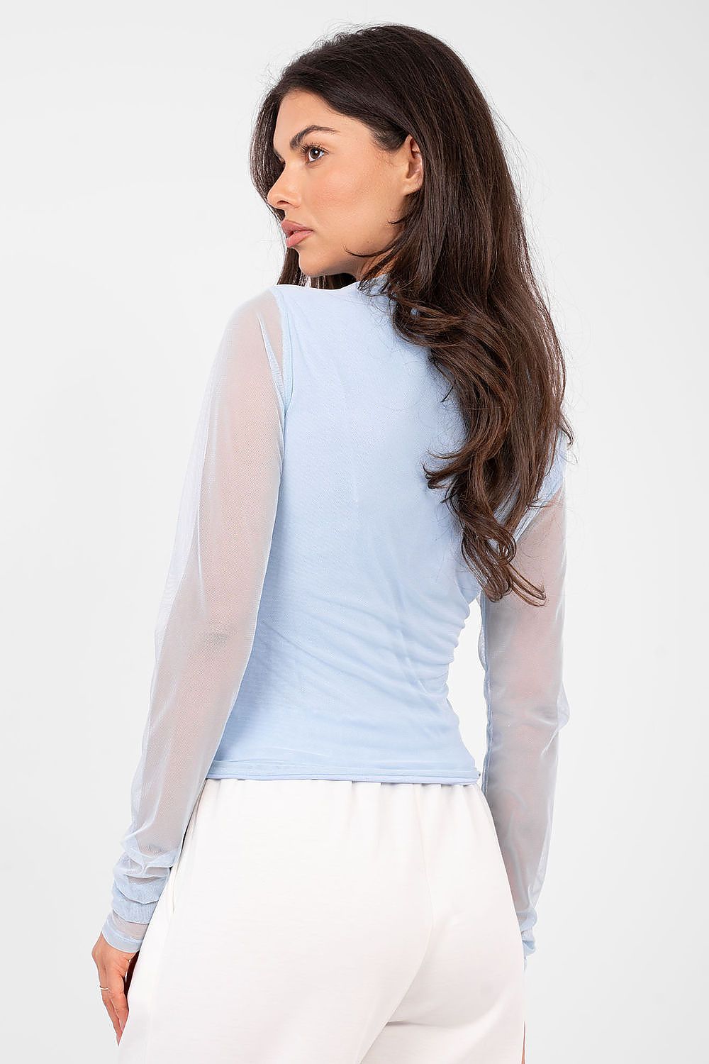 Woman wearing a light blue top with sheer sleeves against a white background