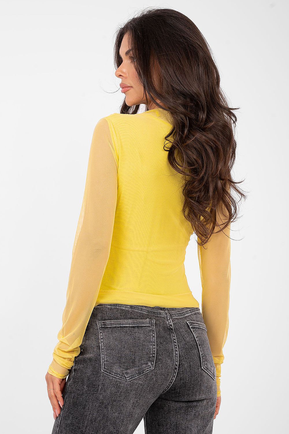 Woman wearing a yellow long-sleeve top and gray pants on a white background