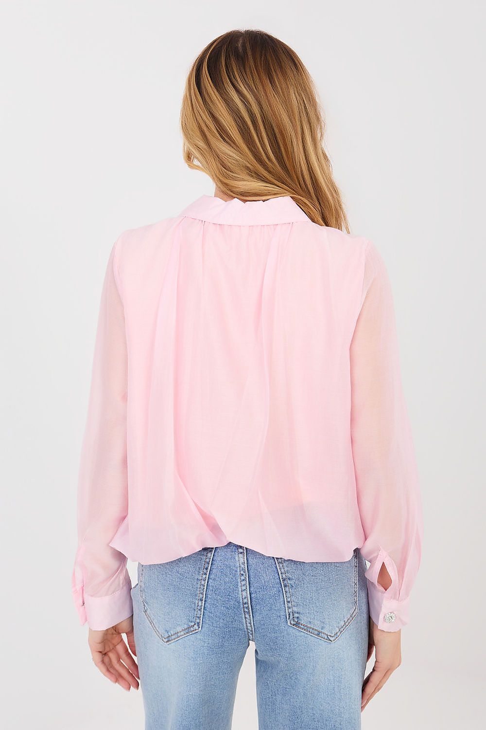 Person wearing a light pink button-up shirt and blue jeans on a white background