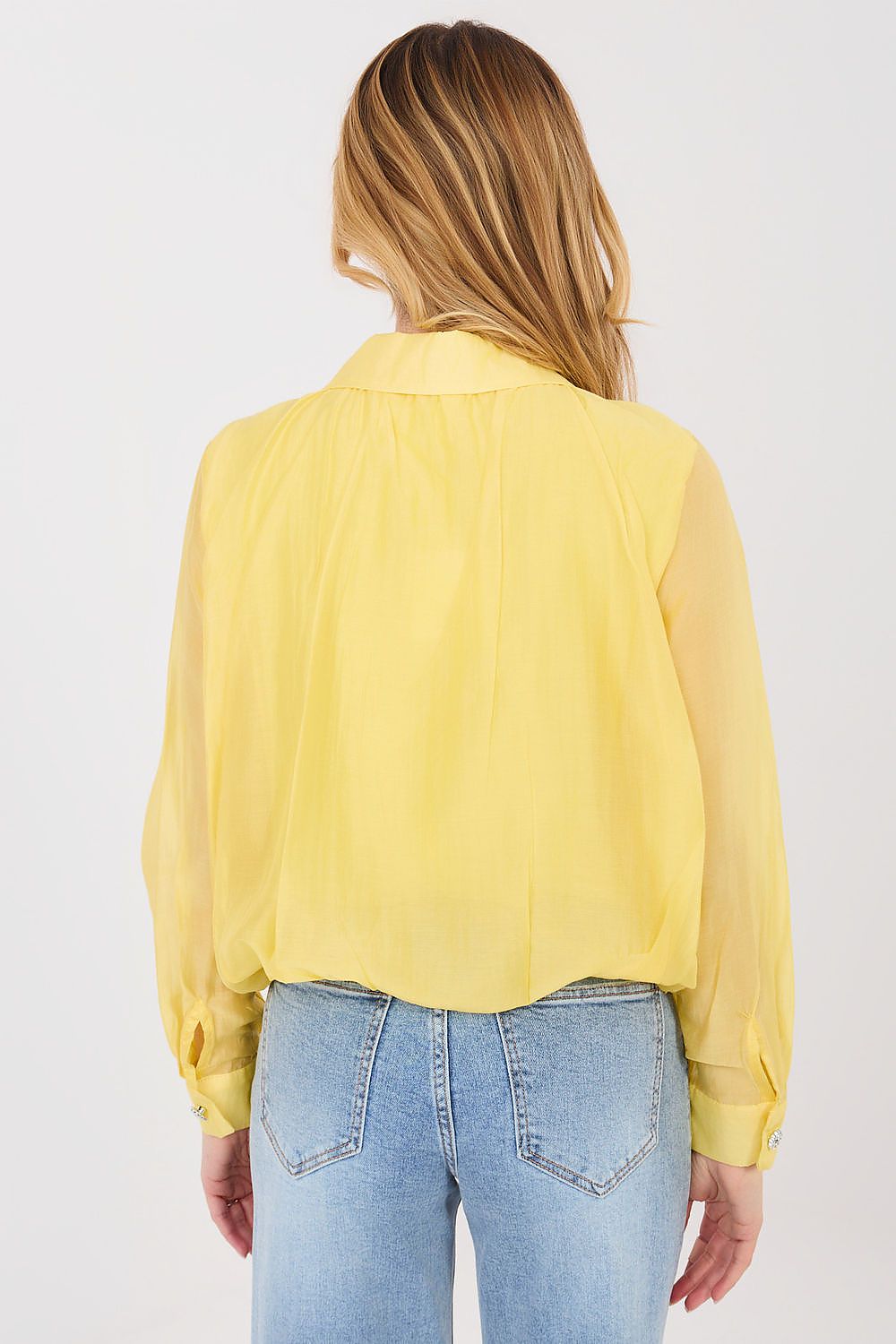 Person wearing a yellow blouse and blue jeans on a white background