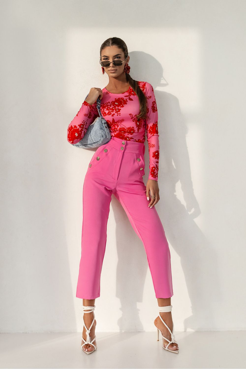 Woman in a pink outfit with floral details against a white background