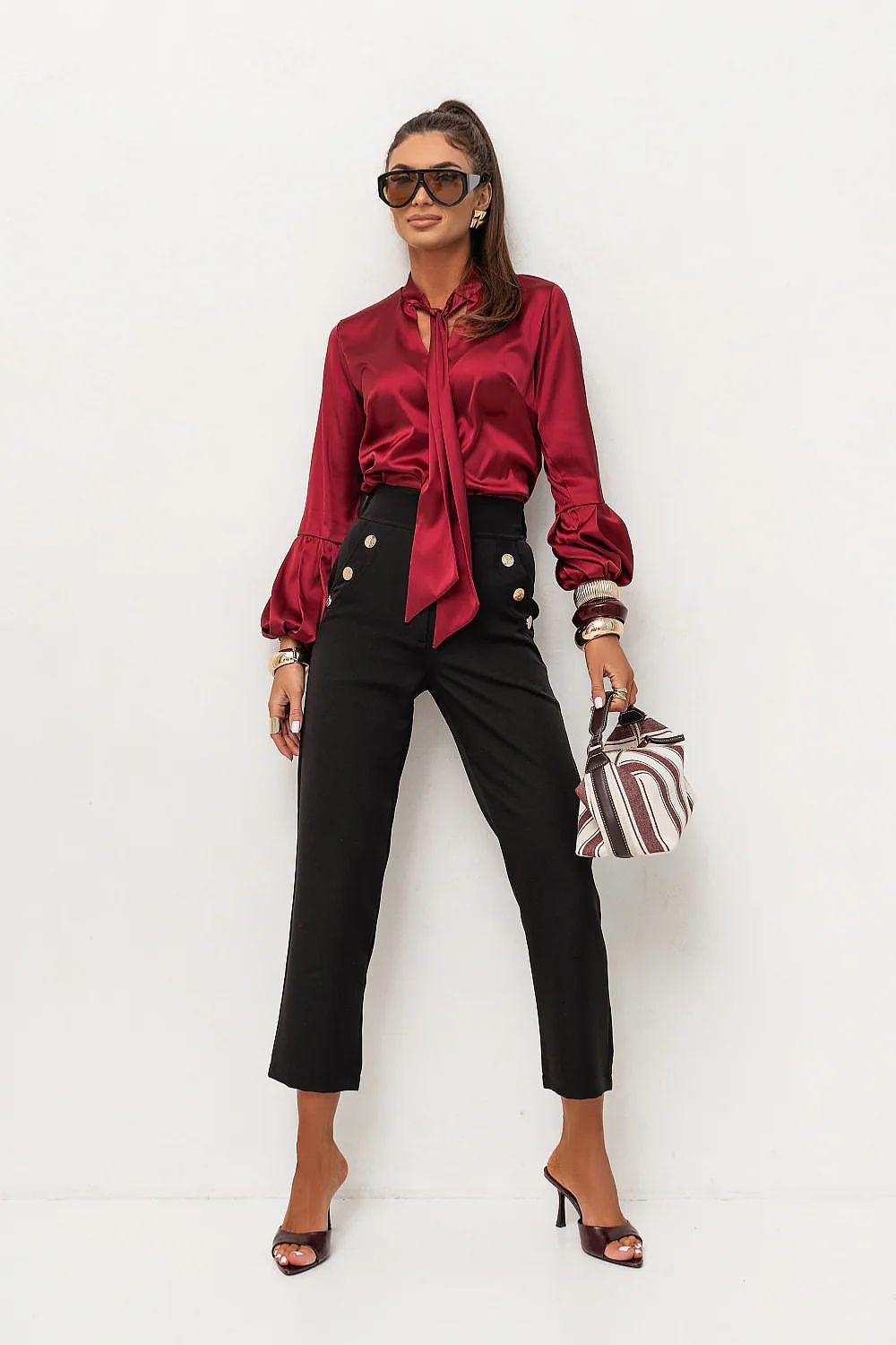 Woman wearing a red satin shirt and black pants with a white background