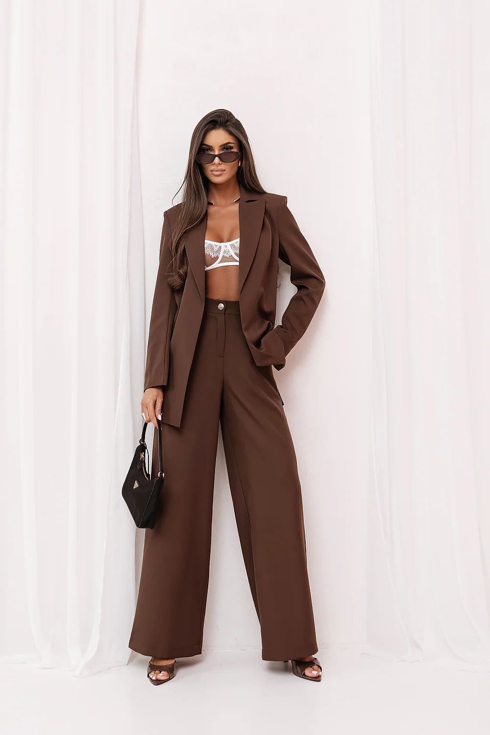 Woman wearing a brown suit with a white top against a white background