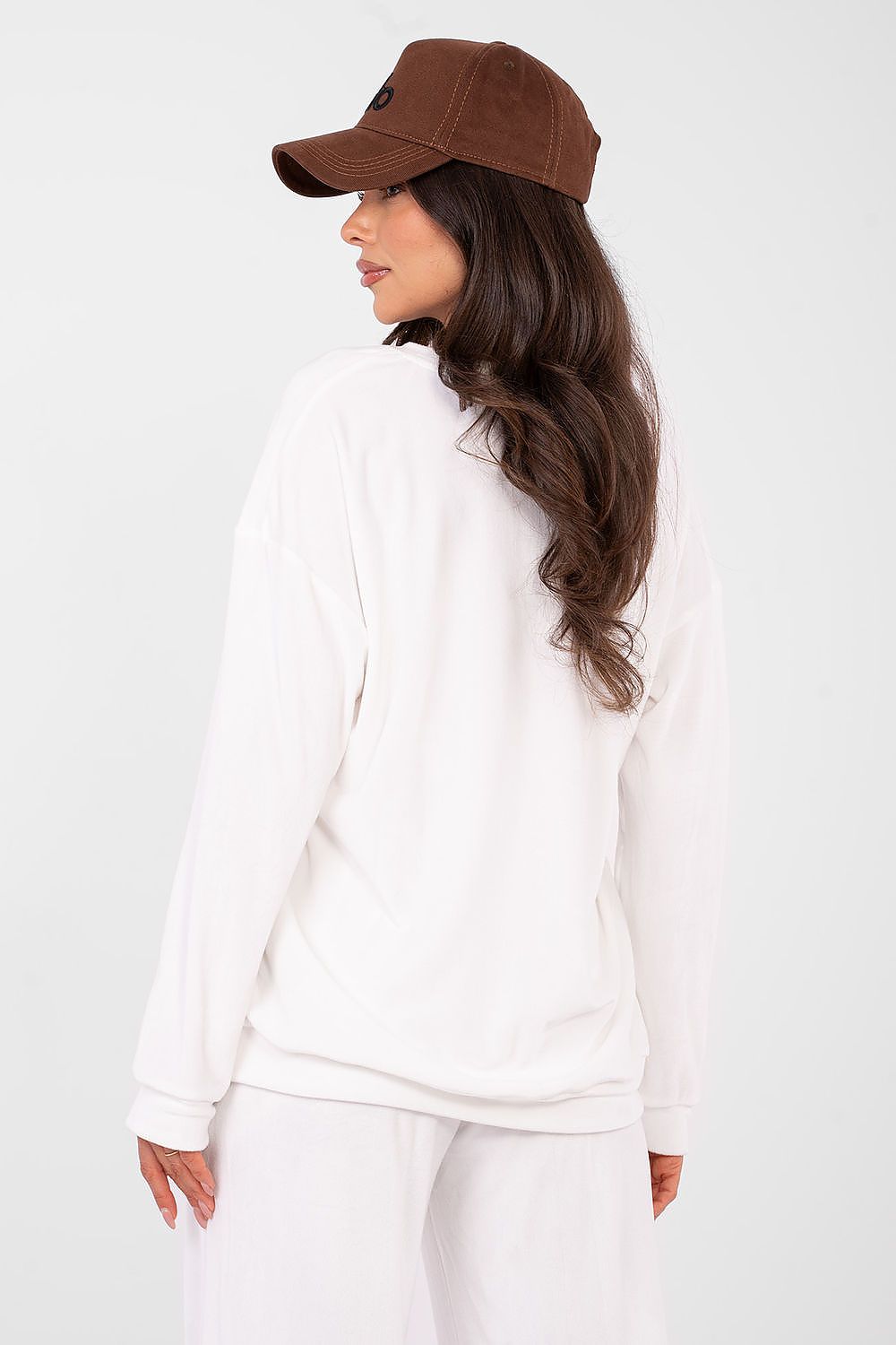 Woman wearing a white outfit and brown cap on a white background