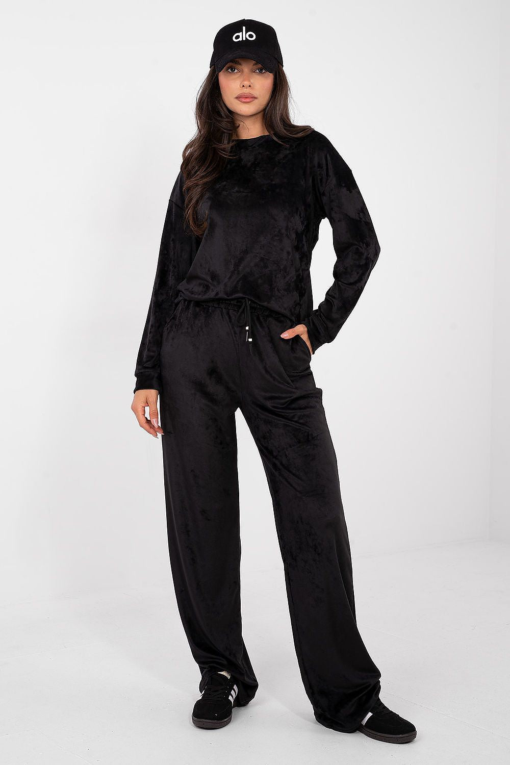 Woman wearing a black tracksuit and cap on a white background