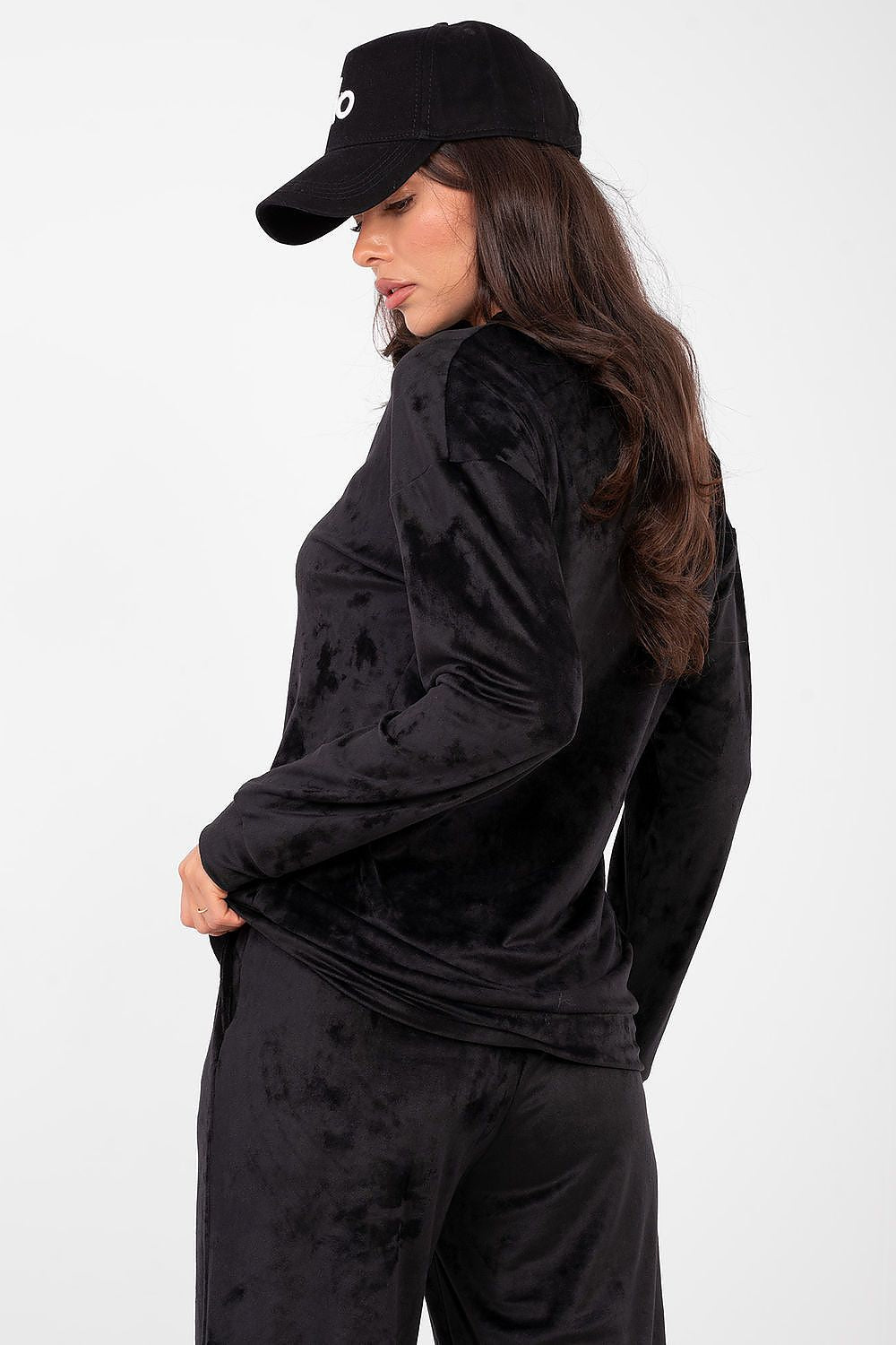 Person wearing a black distressed jacket and pants with a matching cap on a white background