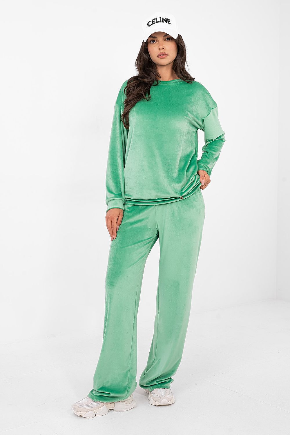 Woman wearing a green velvet outfit with a white background