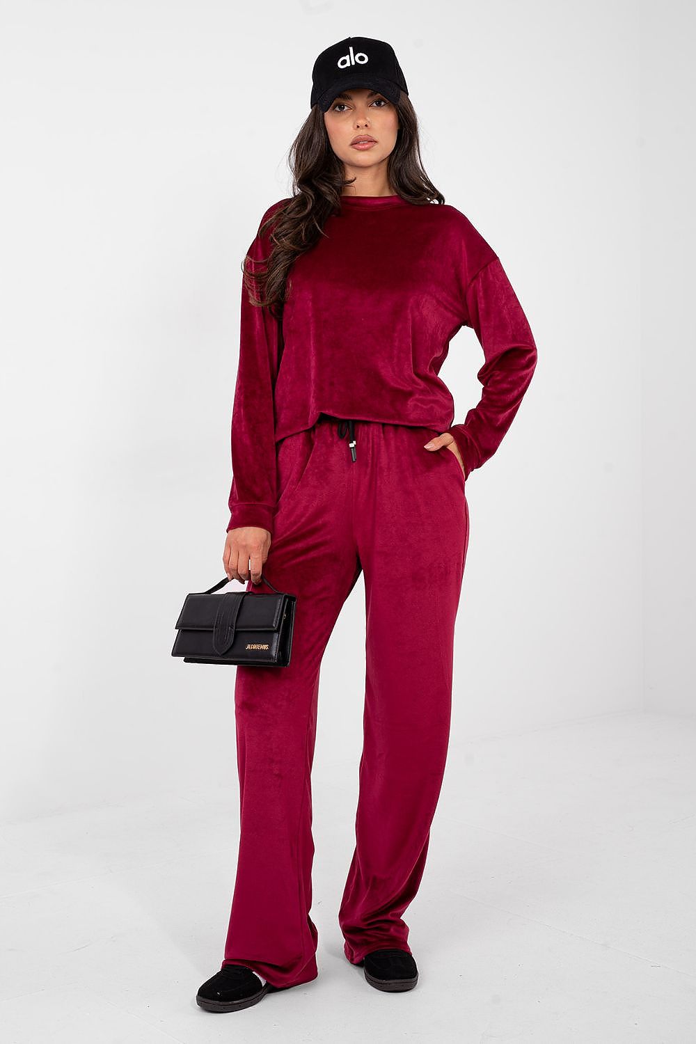 Woman wearing a red outfit with a black cap and handbag on a white background