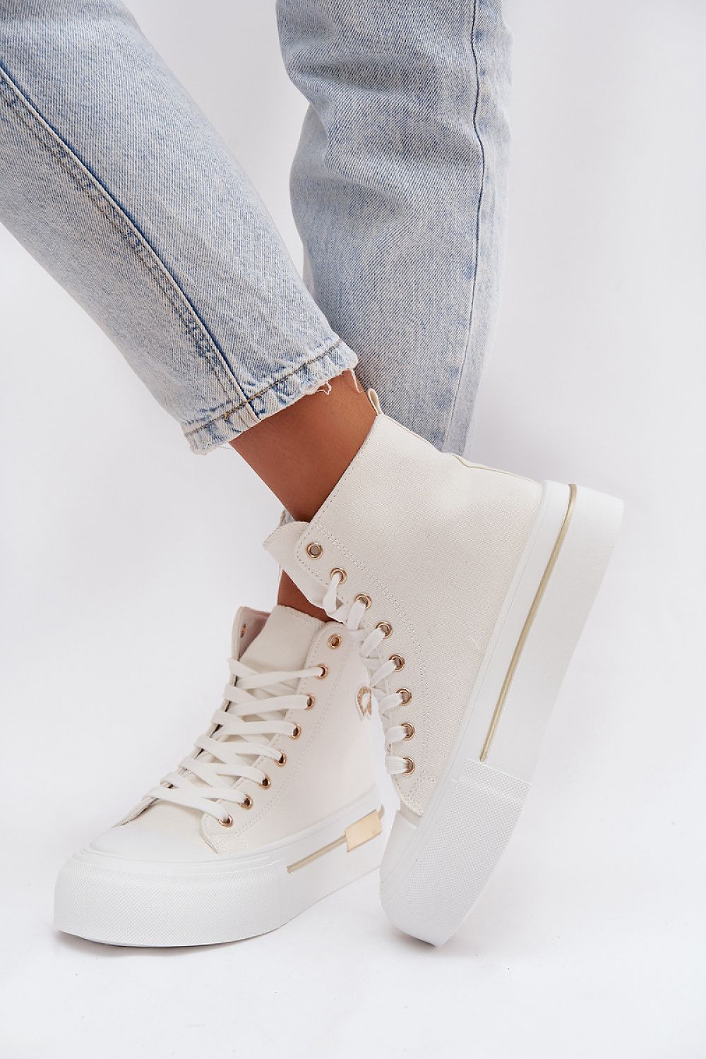 White high-top sneakers with gold accents worn with light blue jeans on a white background