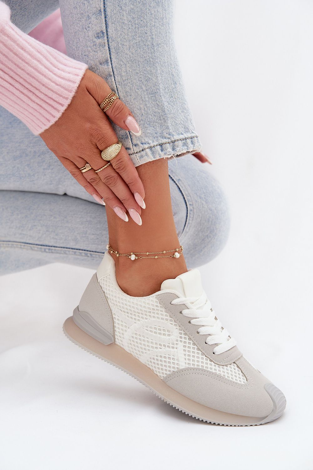 White sneaker worn with light gray pants on a white background