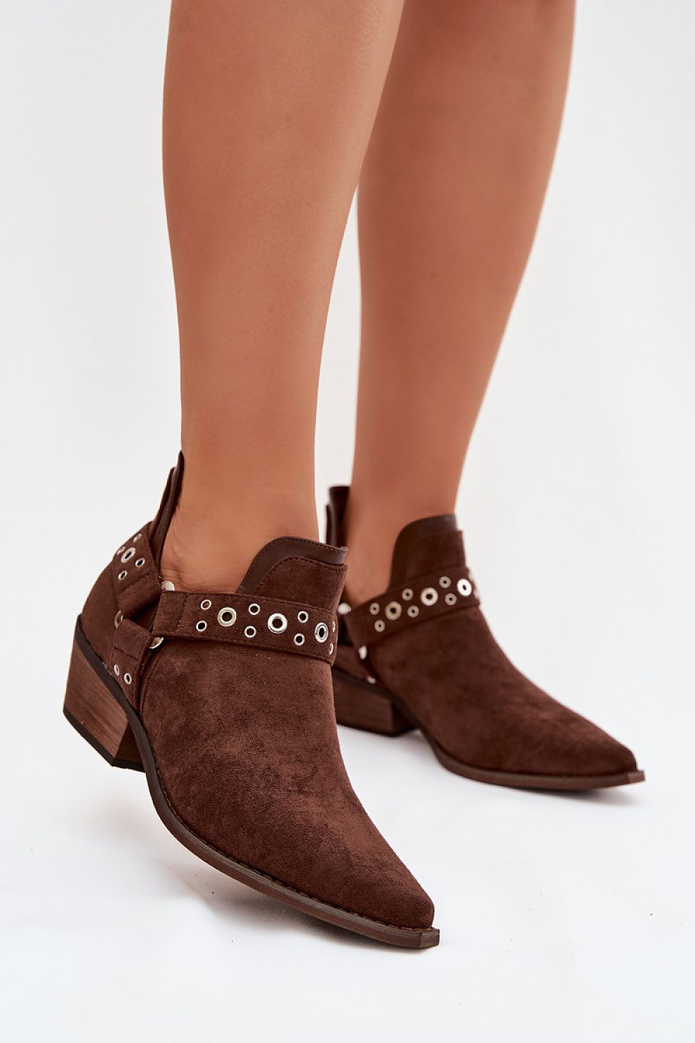 Brown suede ankle boots with decorative straps on a white background