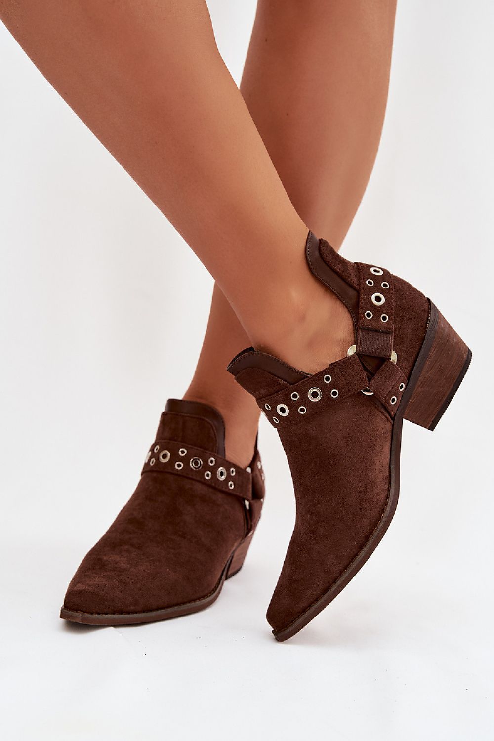 Brown suede ankle boots with decorative straps on a white background
