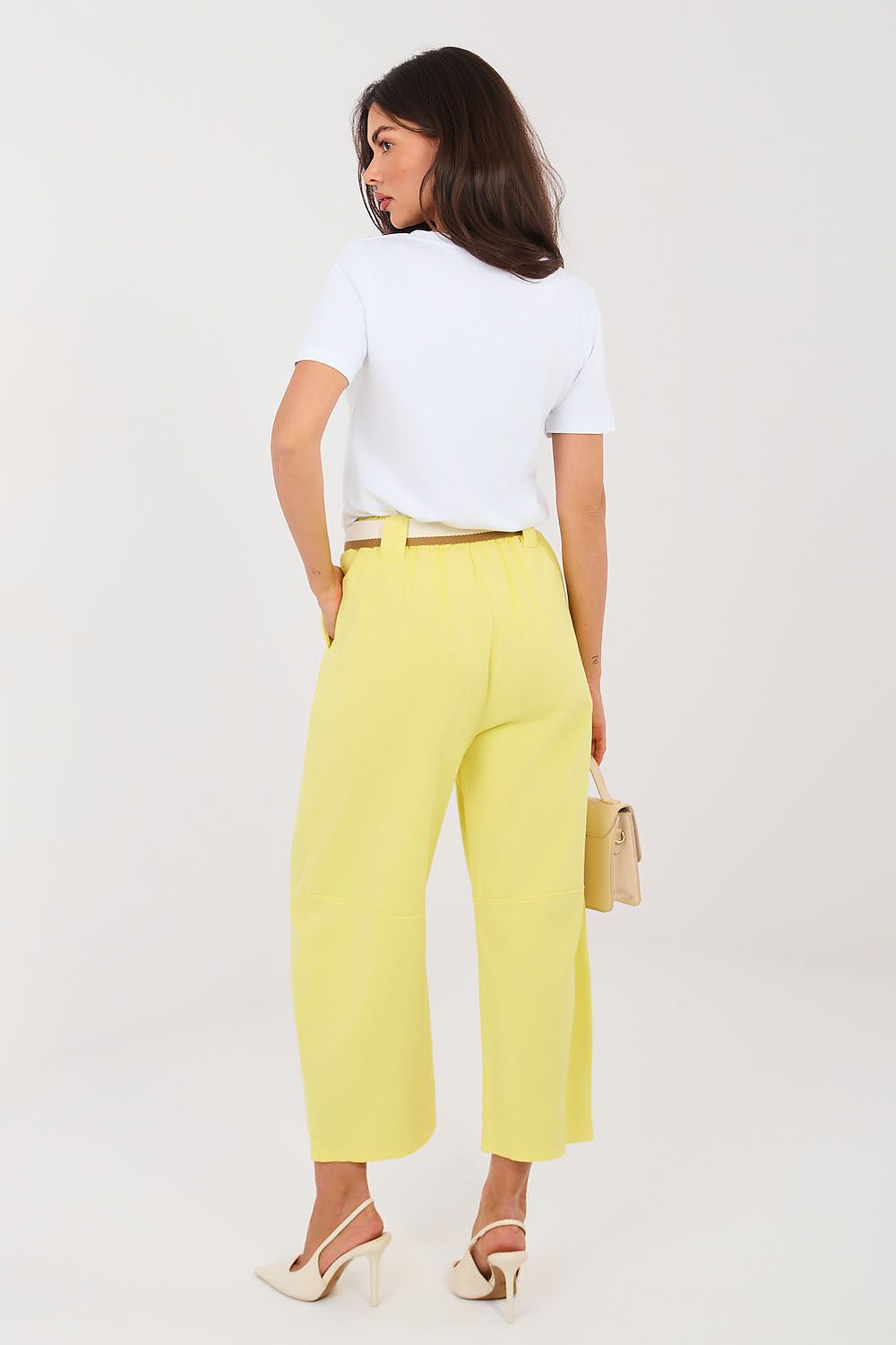Woman wearing a white top and yellow pants on a white background