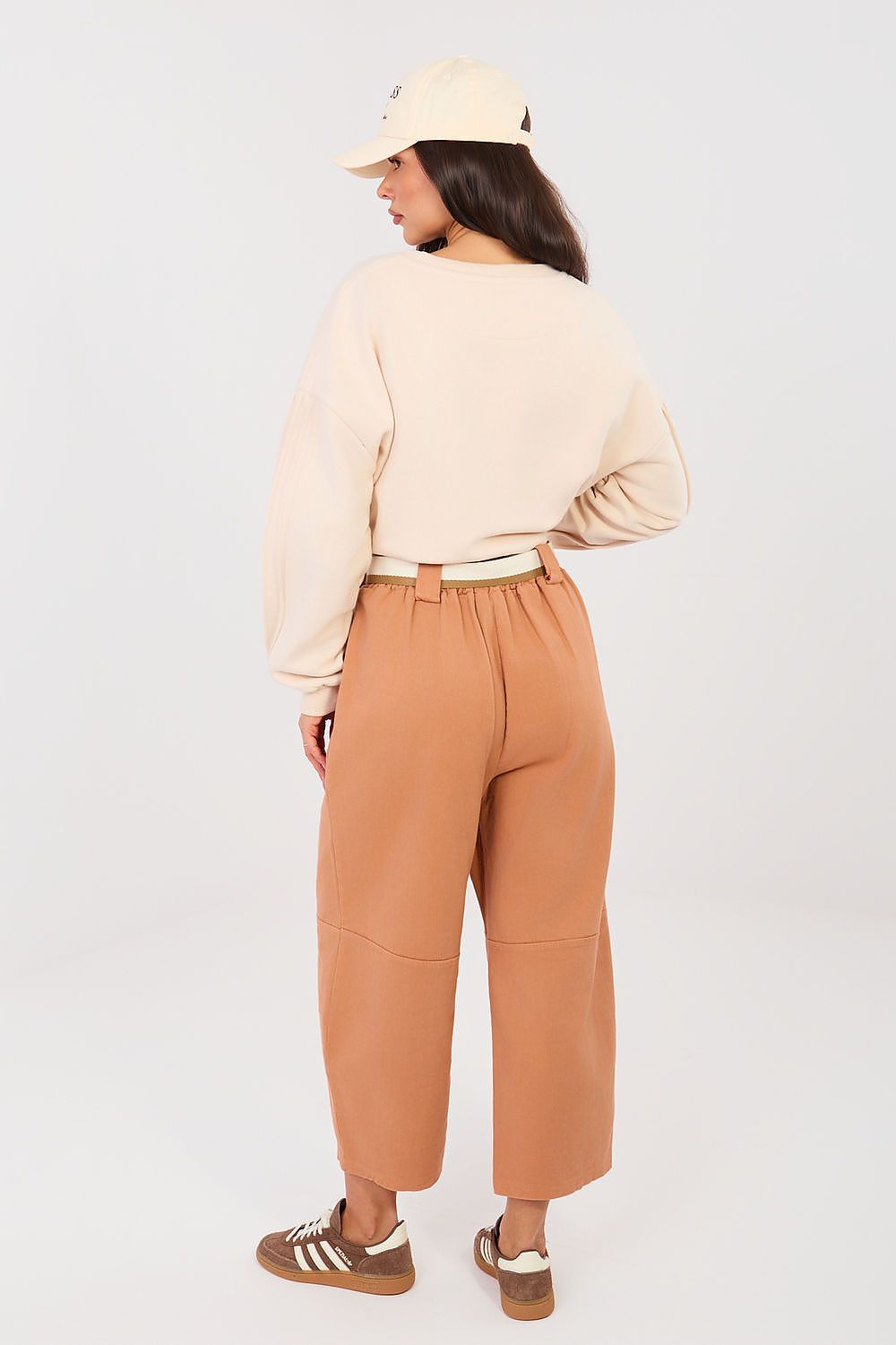Person wearing a beige sweater and tan pants on a white background