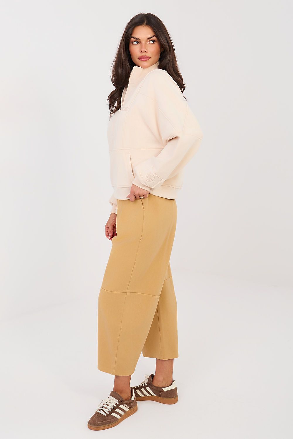 Woman wearing a beige sweater and yellow pants on a white background