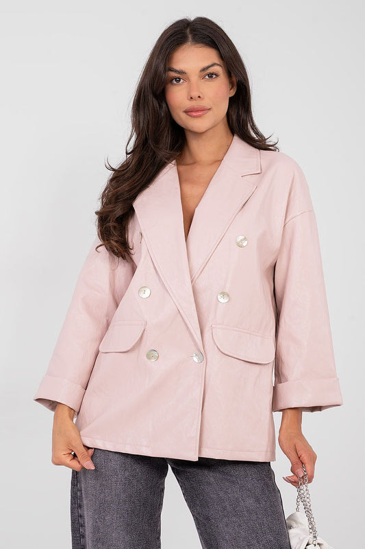 Woman wearing a light pink blazer with a plain background