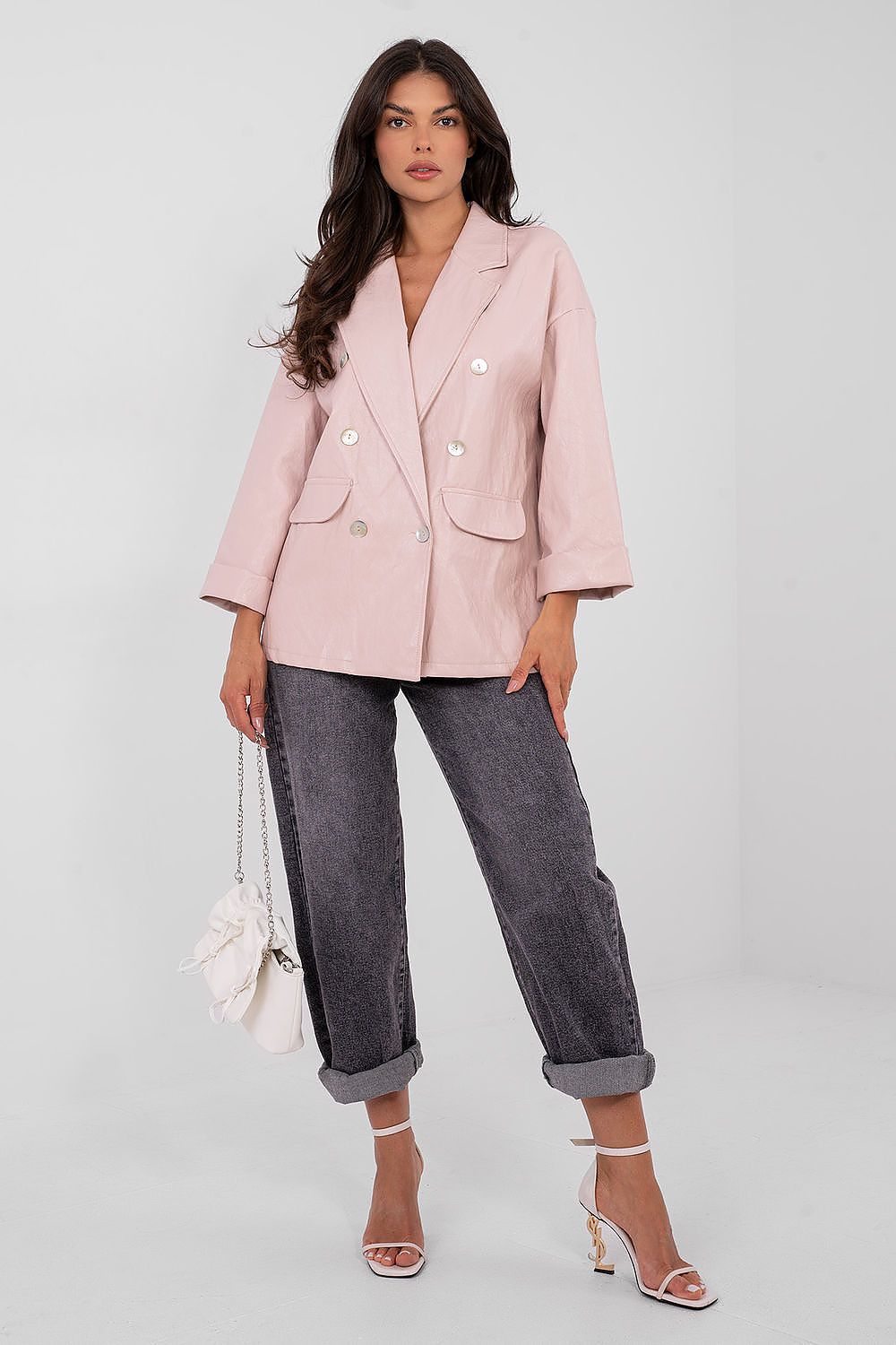 Woman wearing a pink blazer and gray jeans against a white background