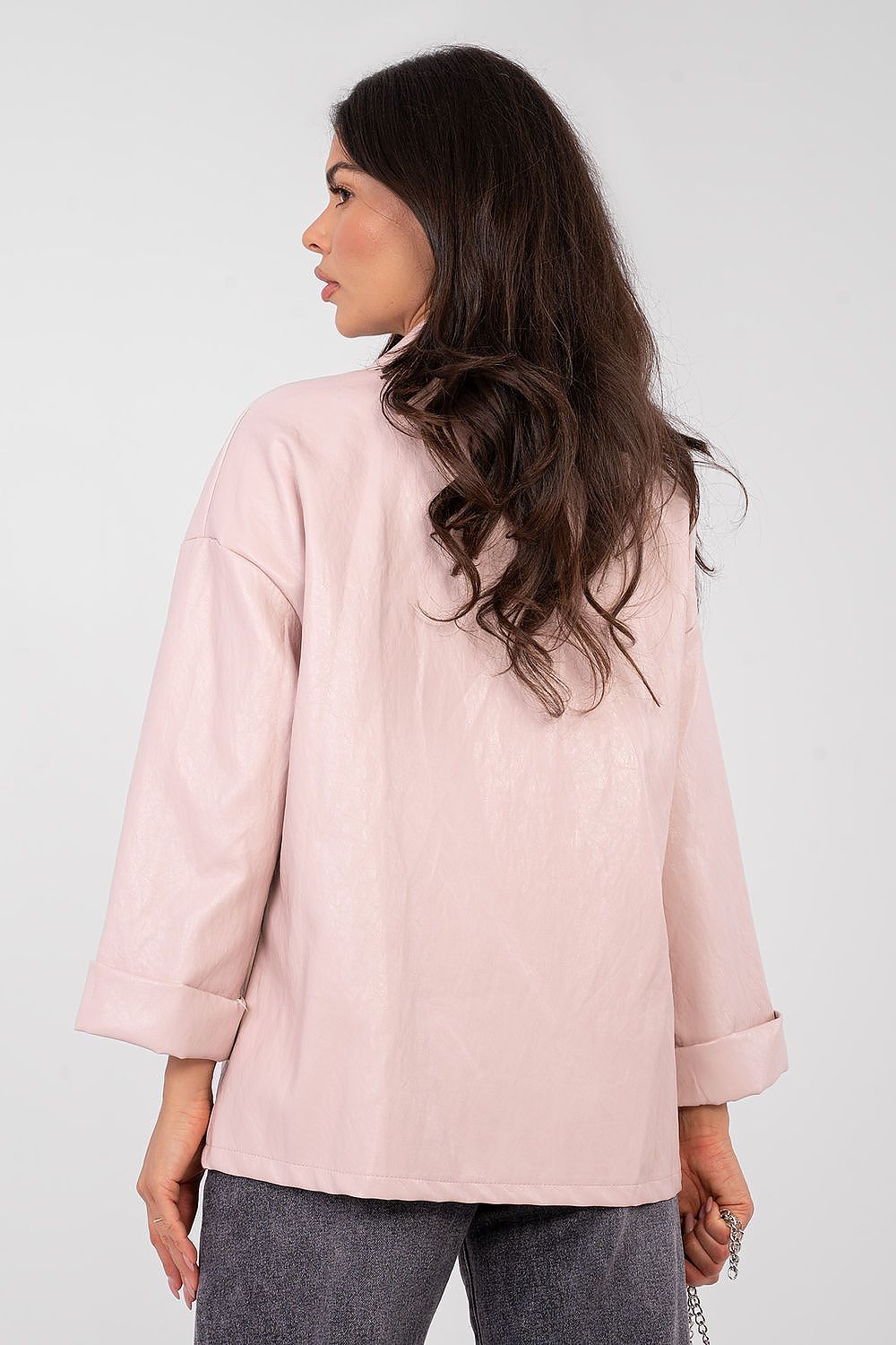 Woman wearing a light pink jacket on a plain background