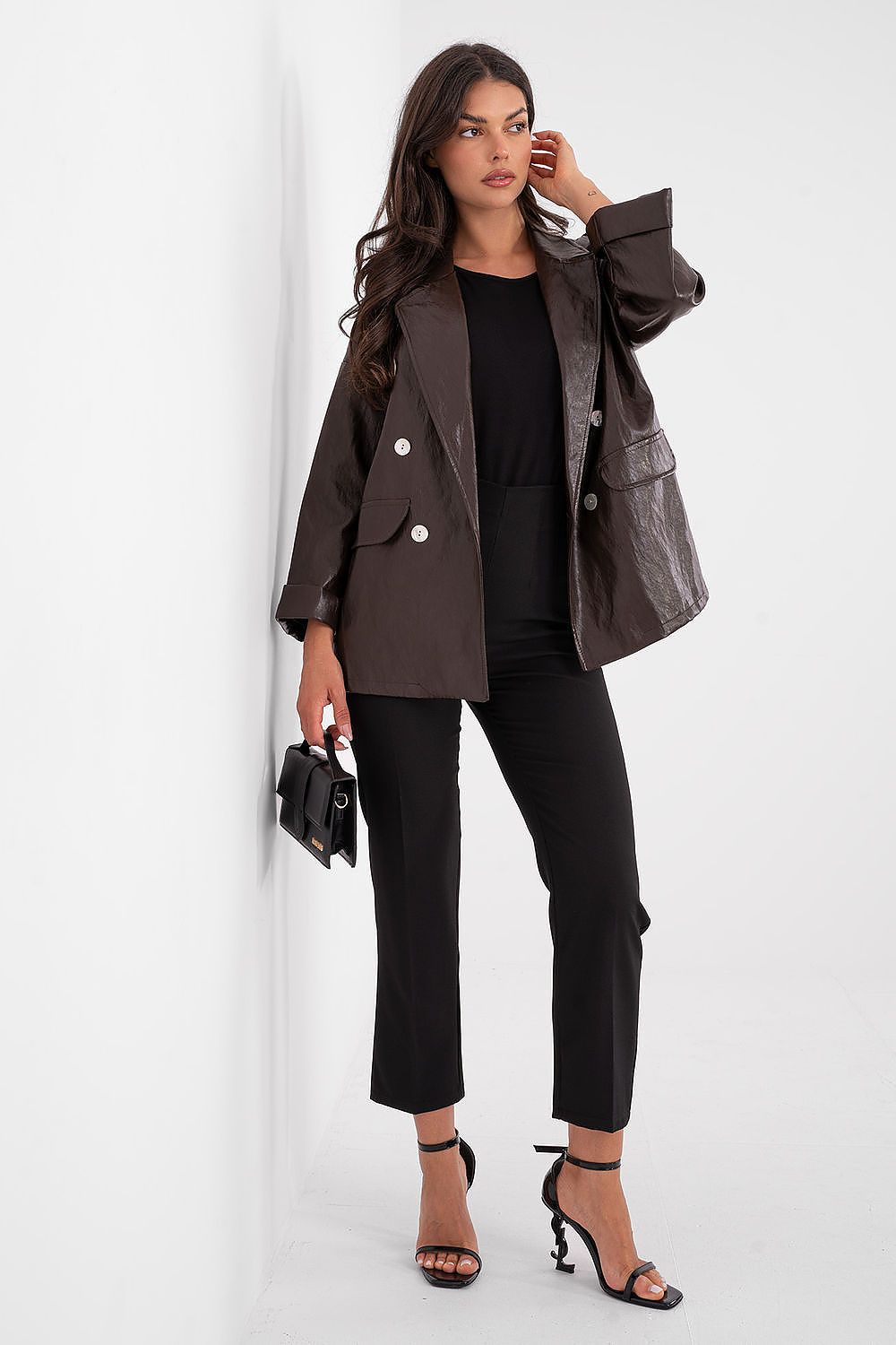 Woman wearing a brown leather jacket and black pants against a white background