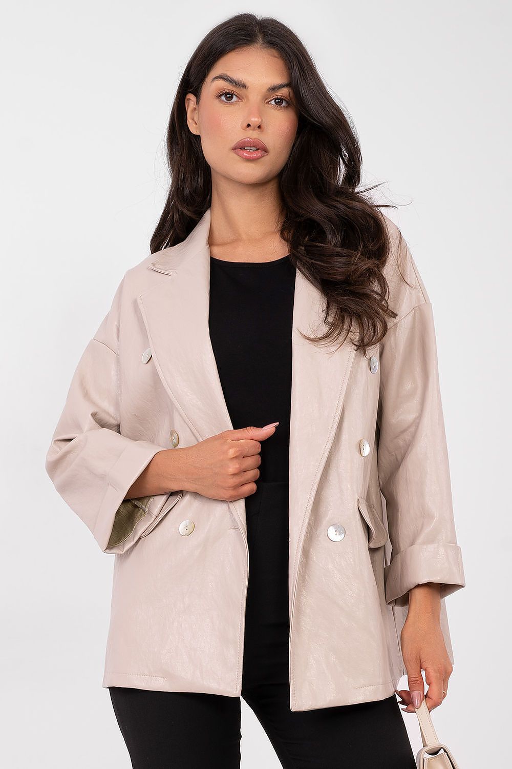 Woman wearing a beige jacket over a black top on a white background