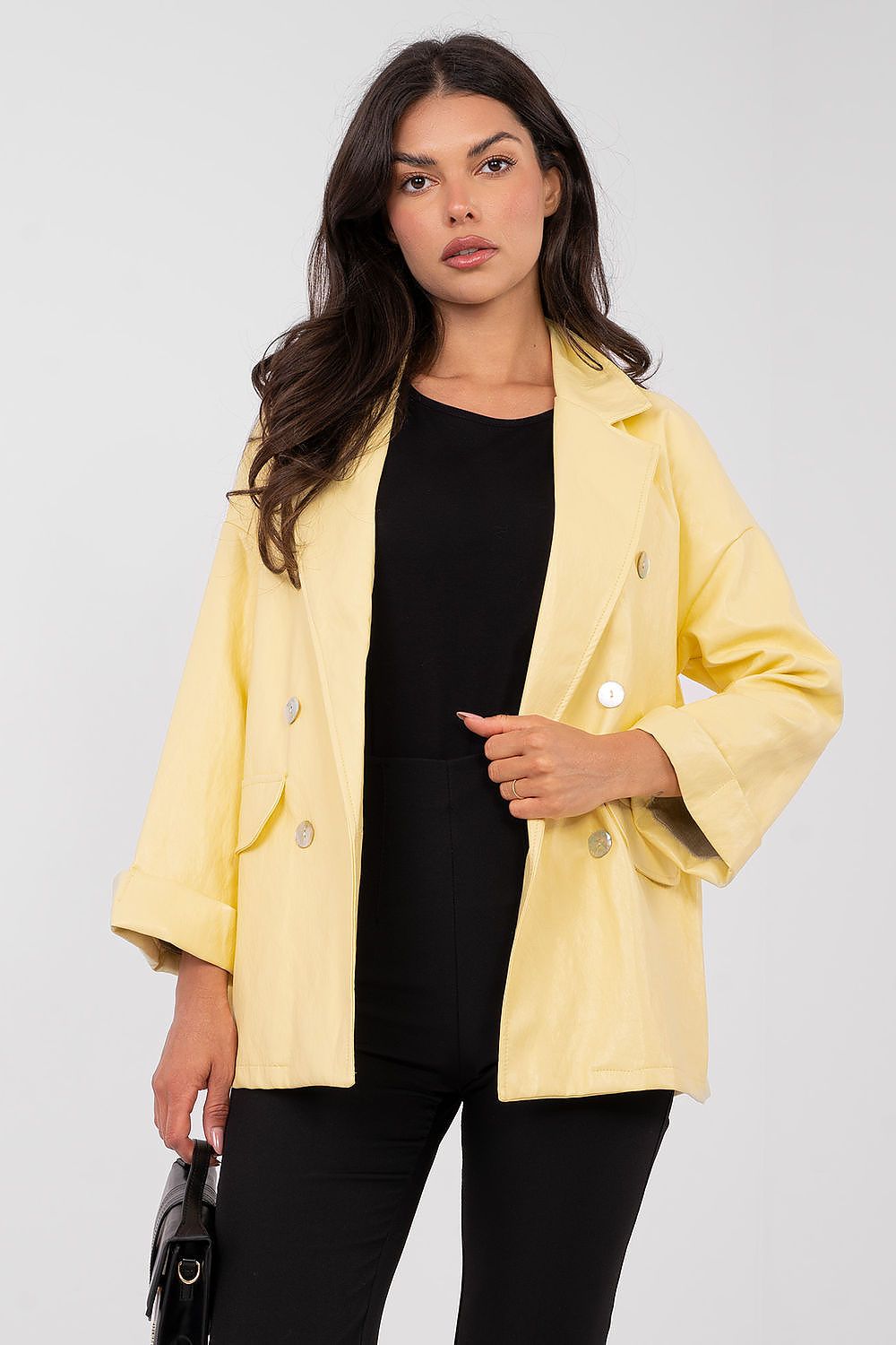 Woman wearing a yellow jacket over a black top on a white background