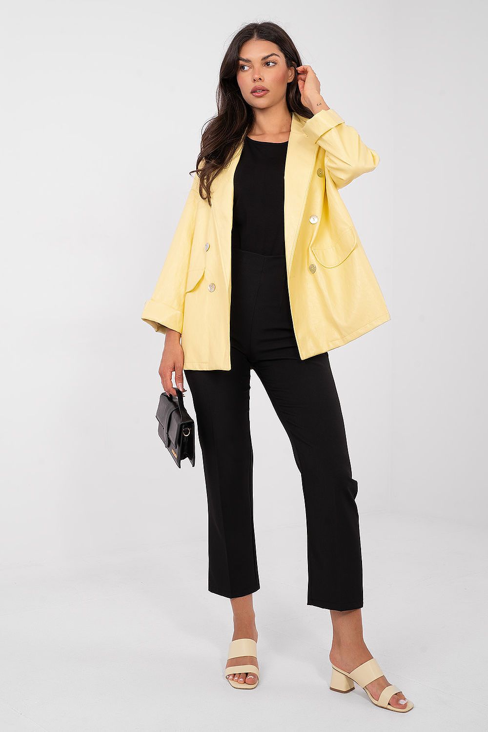 Woman wearing a yellow jacket over a black outfit on a white background